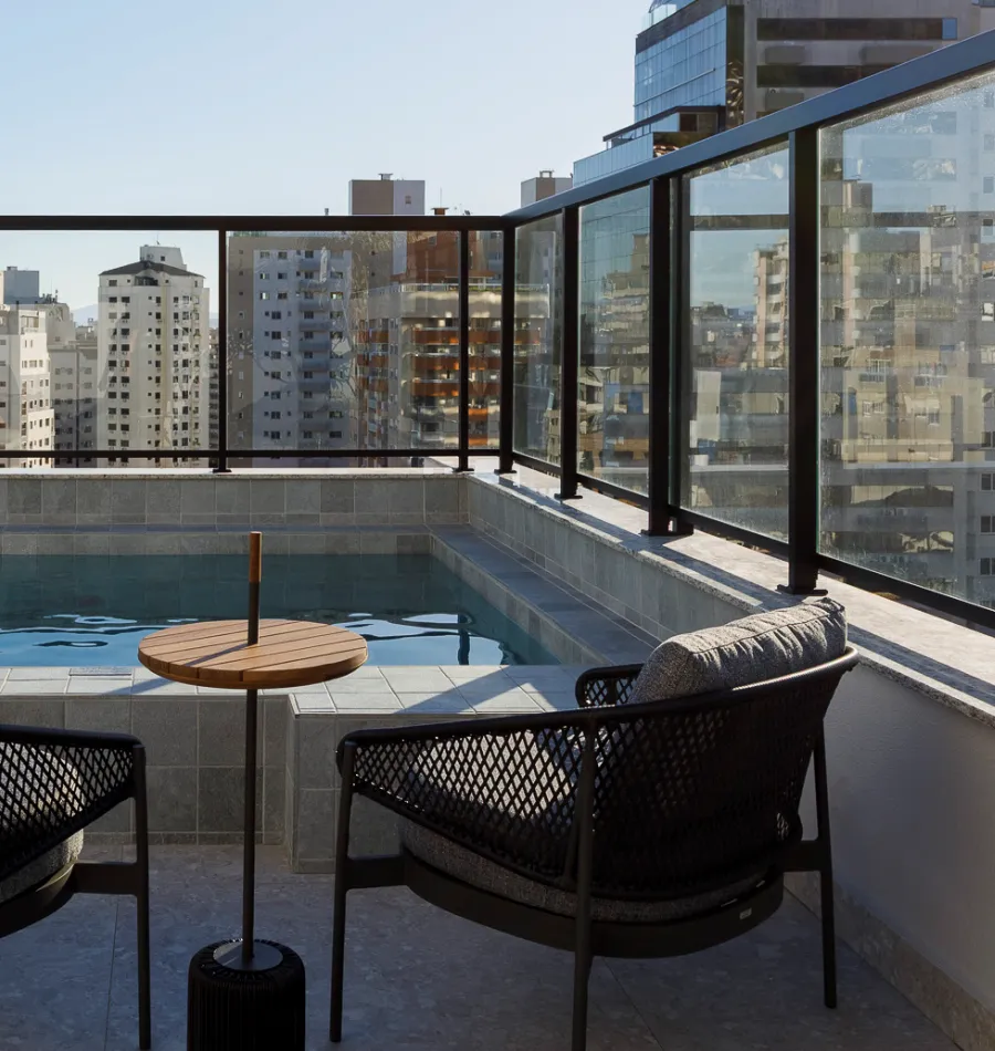 Terraço da piscina do Vila de Algarve, com poltronas e mesa lateral